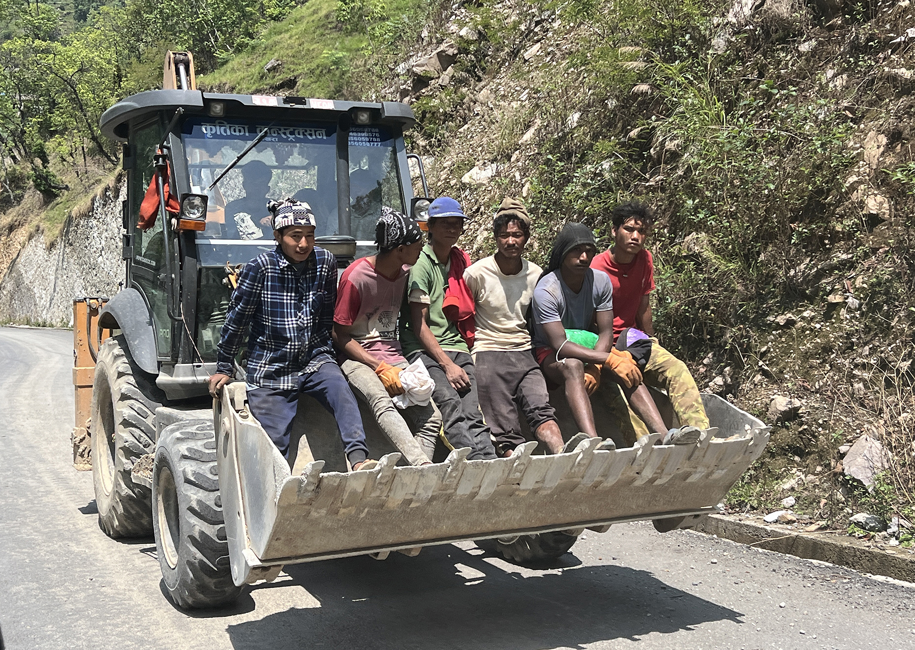 डोजरमा यात्रा गर्दै श्रमिक