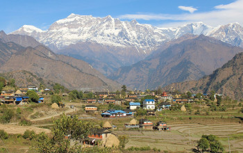 म्याग्दीकाे ताकम गाउँ र पृष्ठभूमिमा देखिएको गुर्जा हिमाल